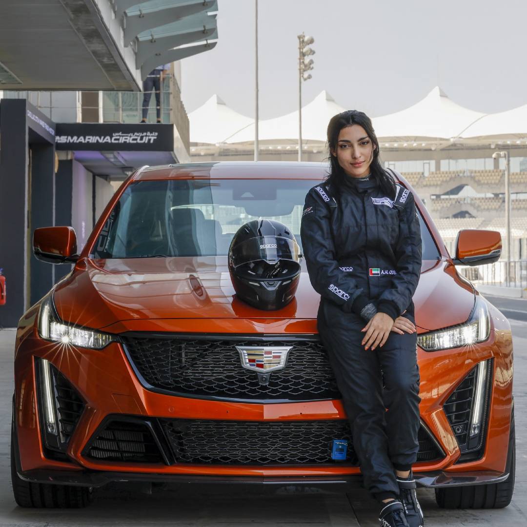 Driver Amna Al Qubaisi sitting on the Cadillac car.