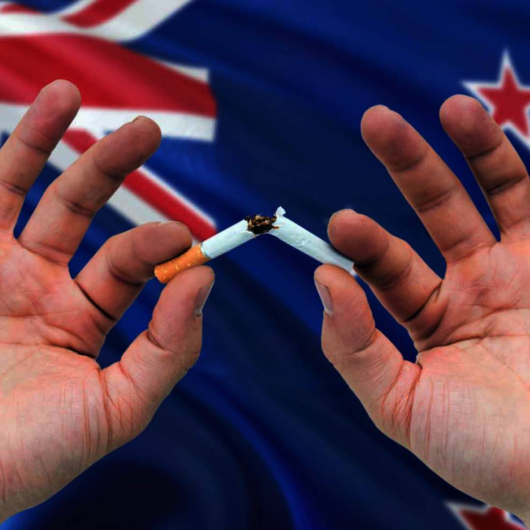 Breaking a cigarette in front of the New Zealand flag.